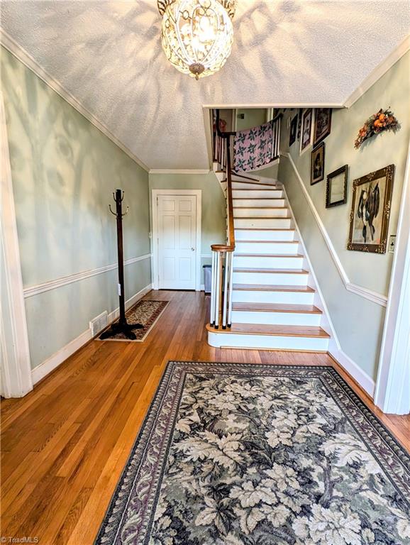 stairway with wood-type flooring, a textured ceiling, and crown molding