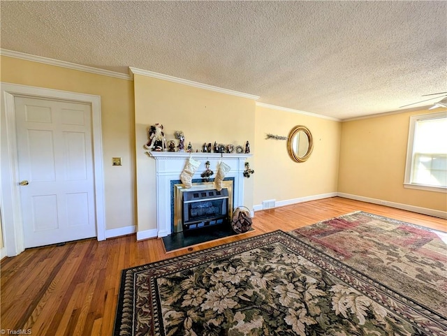 living room with hardwood / wood-style floors, a textured ceiling, crown molding, and ceiling fan