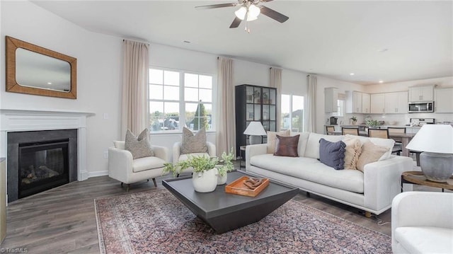 living room with wood finished floors, baseboards, recessed lighting, ceiling fan, and a glass covered fireplace