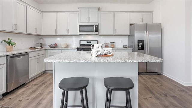 kitchen featuring a breakfast bar area, light wood-style floors, tasteful backsplash, and appliances with stainless steel finishes