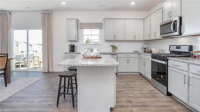 kitchen featuring stainless steel appliances, backsplash, a breakfast bar, and a center island