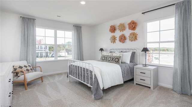 bedroom featuring light colored carpet, baseboards, and multiple windows