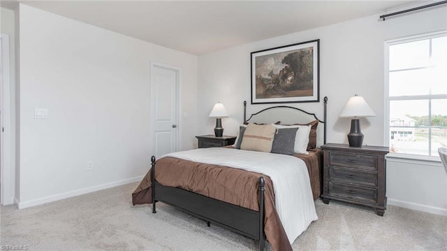 bedroom featuring baseboards, multiple windows, and light colored carpet