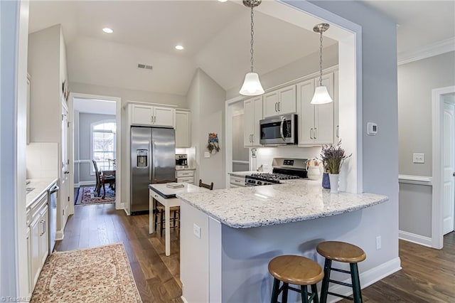 kitchen with appliances with stainless steel finishes, decorative light fixtures, white cabinetry, kitchen peninsula, and light stone countertops