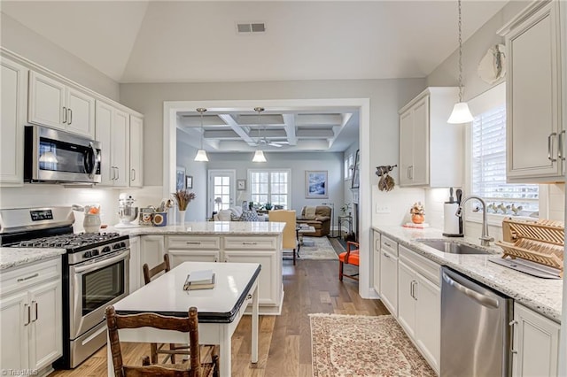 kitchen featuring coffered ceiling, sink, decorative light fixtures, appliances with stainless steel finishes, and beam ceiling