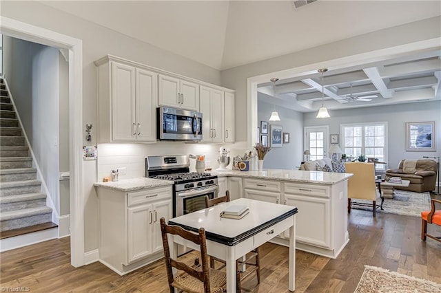 kitchen featuring beamed ceiling, stainless steel appliances, coffered ceiling, and white cabinets