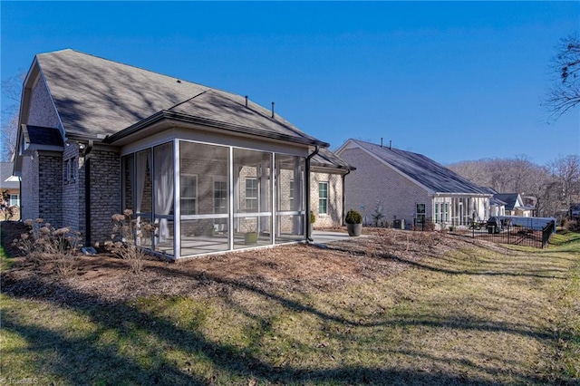 rear view of property with a sunroom and a lawn