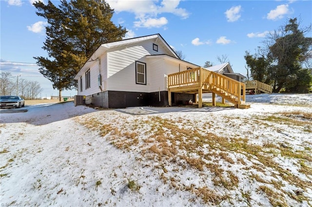 snow covered back of property featuring a wooden deck