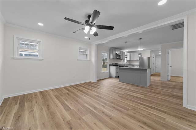 unfurnished living room with crown molding, ceiling fan, sink, and light wood-type flooring