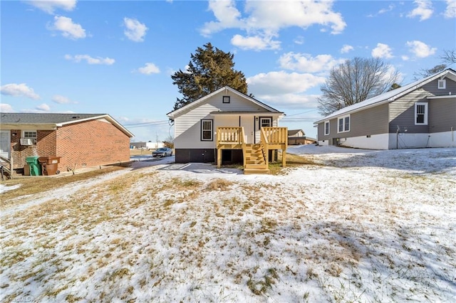 snow covered back of property with a wooden deck