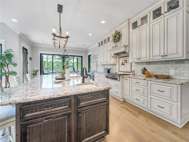 1579 Sunset Pointe Dr, Salisbury, NC 28146 - kitchen with tasteful backsplash, a sink, stainless steel gas cooktop, light wood-style floors, and a notable chandelier