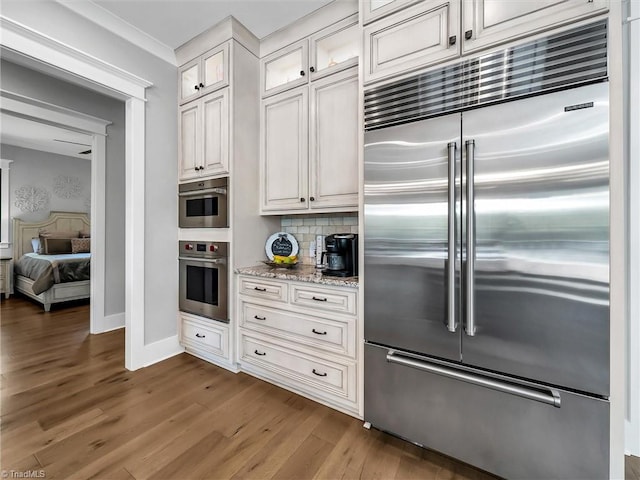 1579 Sunset Pointe Dr, Salisbury, NC 28146 - kitchen featuring wood finished floors, light stone countertops, baseboards, glass insert cabinets, and stainless steel built in refrigerator