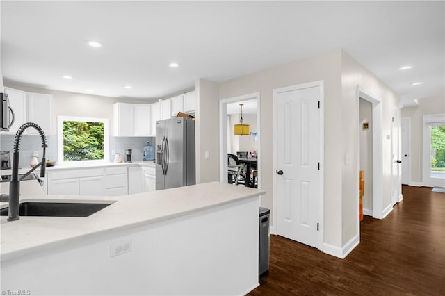 kitchen featuring appliances with stainless steel finishes, a sink, backsplash, dark wood-type flooring, and white cabinets