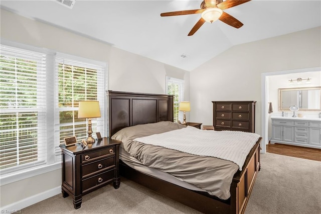 bedroom with light colored carpet, lofted ceiling, baseboards, connected bathroom, and ceiling fan