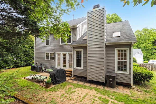 rear view of property with a chimney, french doors, a patio area, and central AC