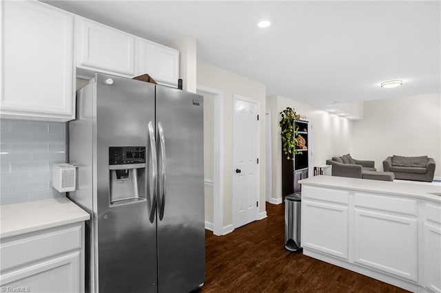 kitchen featuring stainless steel fridge, open floor plan, white cabinetry, light countertops, and dark wood finished floors