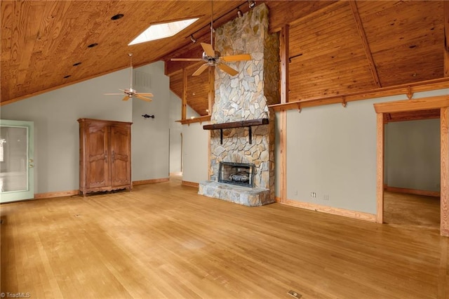 unfurnished living room featuring a skylight, light hardwood / wood-style flooring, wooden ceiling, ceiling fan, and a fireplace