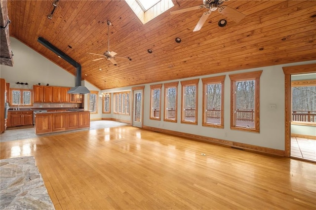 unfurnished living room featuring sink, wood ceiling, a skylight, ceiling fan, and light hardwood / wood-style floors