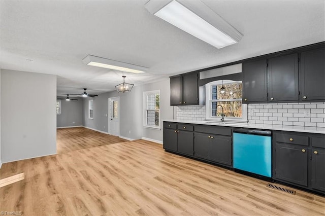 kitchen with tasteful backsplash, dishwasher, light countertops, light wood-type flooring, and a sink