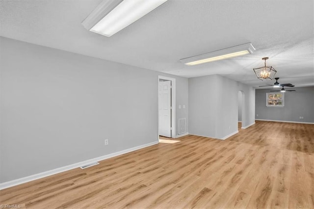 unfurnished room with light wood-style flooring, baseboards, arched walkways, and ceiling fan