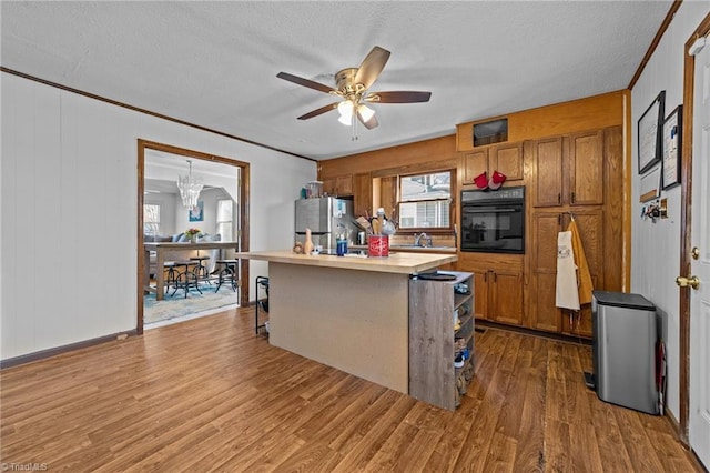 kitchen featuring black oven, a kitchen island, stainless steel fridge, sink, and dark wood-type flooring