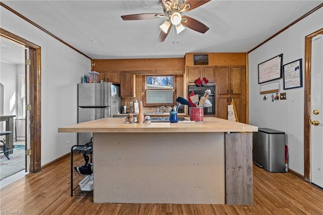 kitchen featuring a kitchen island, light hardwood / wood-style floors, black oven, and crown molding