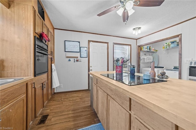 kitchen featuring light wood-type flooring, a textured ceiling, washer / dryer, black appliances, and ornamental molding