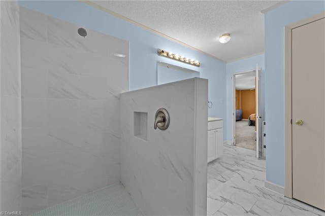 bathroom featuring a textured ceiling, vanity, crown molding, and tiled shower