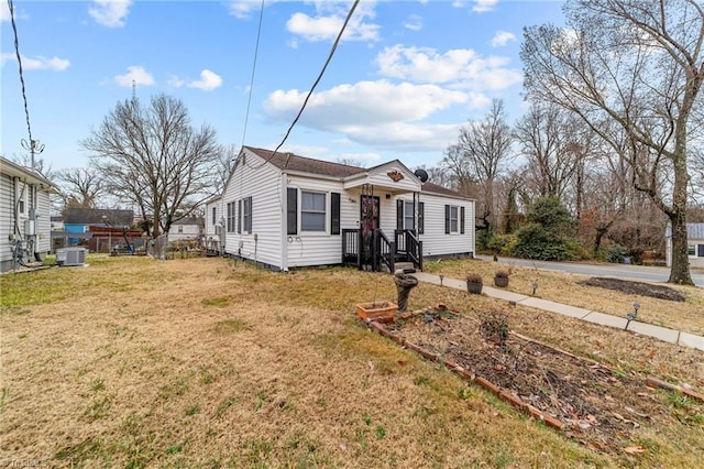 bungalow-style house featuring central air condition unit and a front lawn