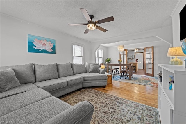 living room with hardwood / wood-style flooring, ceiling fan, french doors, and a textured ceiling