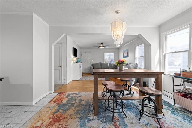 tiled dining room featuring ceiling fan with notable chandelier, crown molding, and a textured ceiling