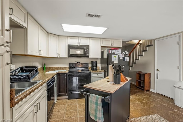 kitchen featuring white cabinetry, wooden counters, and black appliances