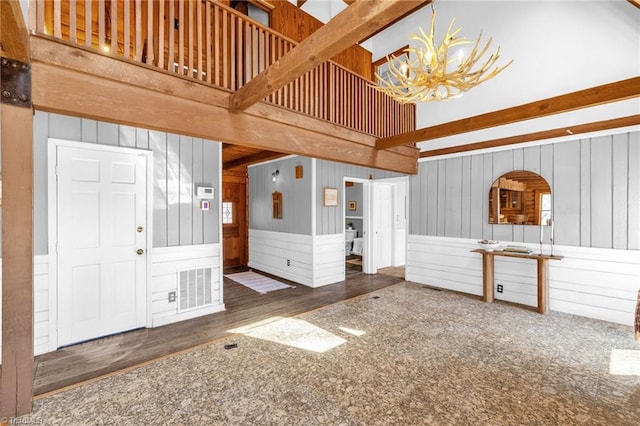 foyer entrance with wood finished floors, visible vents, beam ceiling, a high ceiling, and a chandelier