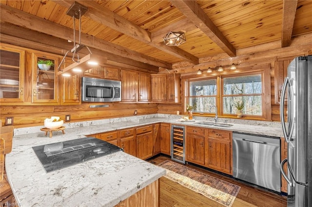 kitchen featuring light stone counters, beverage cooler, a sink, wood-type flooring, and appliances with stainless steel finishes