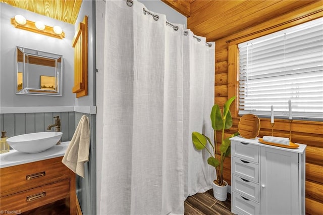 bathroom with vanity, a shower with shower curtain, wood finished floors, and log walls