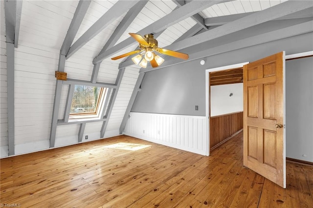 unfurnished room with lofted ceiling with beams, a wainscoted wall, ceiling fan, and hardwood / wood-style flooring