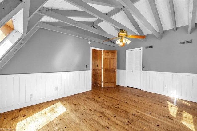 empty room with visible vents, lofted ceiling with beams, and wood-type flooring