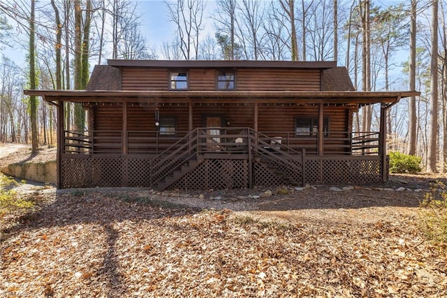 log home with log siding, a porch, and a shingled roof