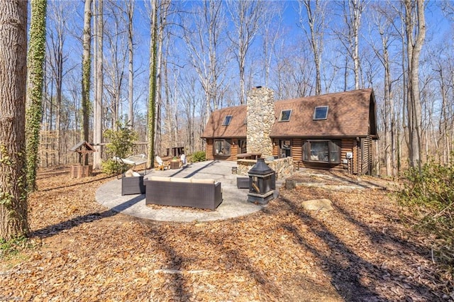 back of property with a patio, roof with shingles, an outdoor hangout area, log exterior, and a chimney