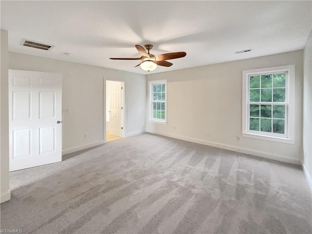 unfurnished room featuring ceiling fan, light colored carpet, and a wealth of natural light