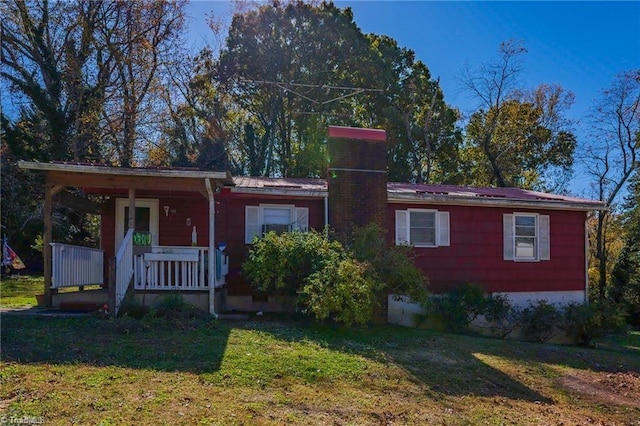 ranch-style house with a chimney, a front lawn, and a porch