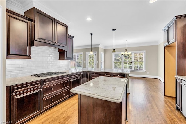 kitchen with stainless steel gas stovetop, hanging light fixtures, dark brown cabinetry, light wood-type flooring, and kitchen peninsula