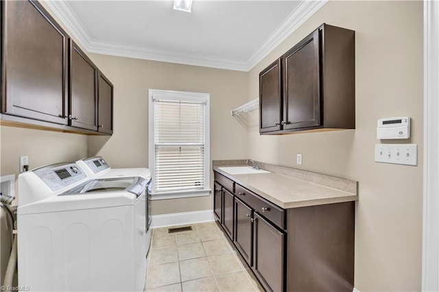 laundry room featuring cabinets, sink, crown molding, washer and dryer, and light tile patterned flooring