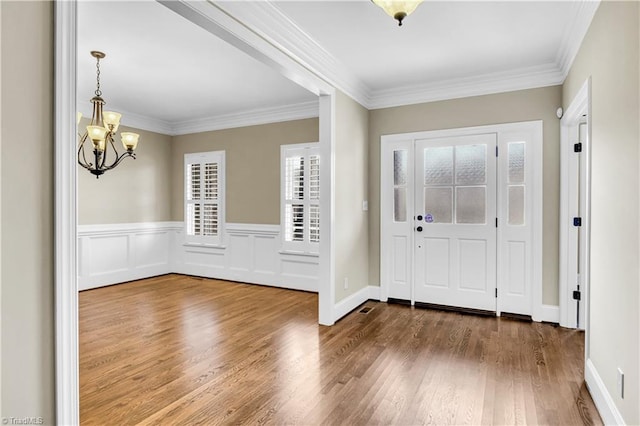 entrance foyer with hardwood / wood-style floors, a chandelier, and ornamental molding