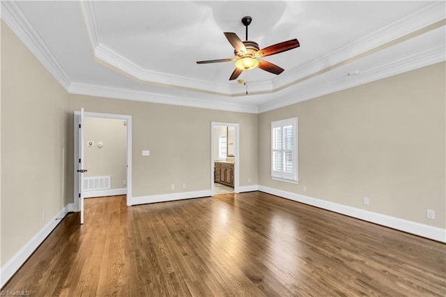 empty room with dark hardwood / wood-style floors, ceiling fan, crown molding, and a tray ceiling