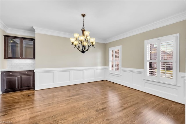 unfurnished dining area featuring hardwood / wood-style floors, an inviting chandelier, and crown molding