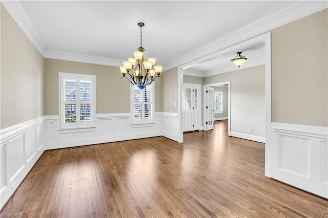 unfurnished dining area featuring hardwood / wood-style flooring, a chandelier, and ornamental molding