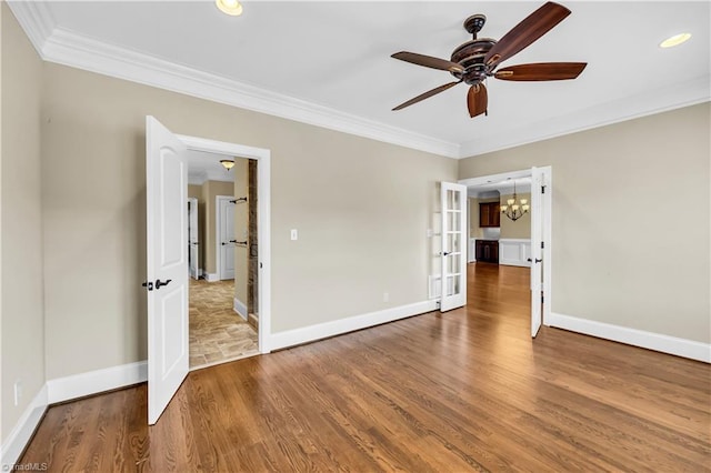 empty room with ceiling fan with notable chandelier, wood-type flooring, ornamental molding, and french doors