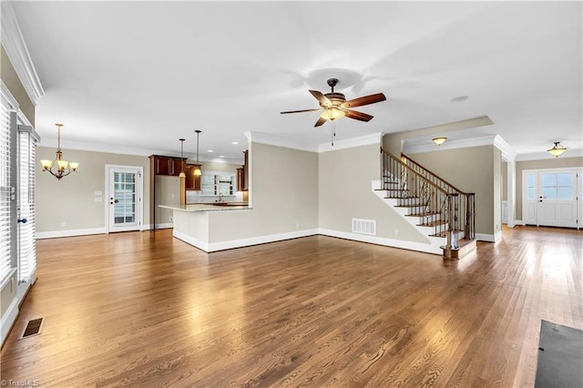 unfurnished living room with ceiling fan with notable chandelier, dark hardwood / wood-style flooring, and ornamental molding