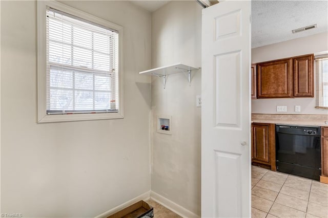 laundry area featuring hookup for a washing machine, light tile patterned floors, and a textured ceiling